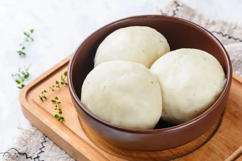 Three balls of fufu in a dark bowl