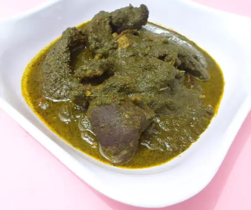 Nigerian black soup with assorted meat in a white dish